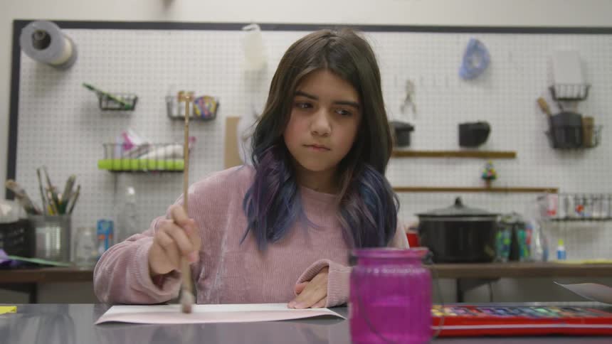 A young girl paints with a brush