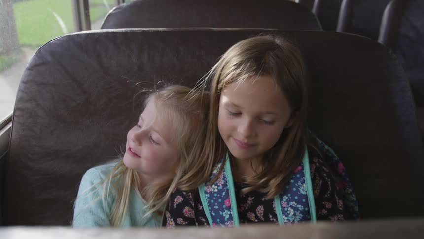 Two young children snuggle up together on a bus
