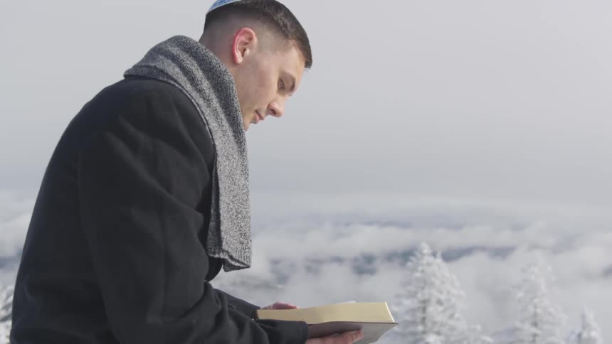 A man wearing a yamaka reads a book