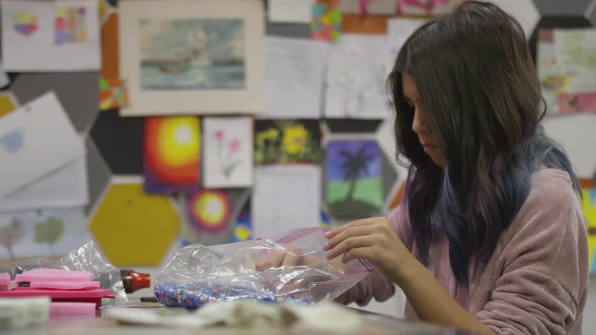 Girl sifting through a bag of beads in an art room
