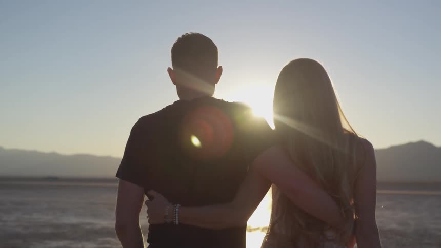 A man and woman walk together outside under the sun