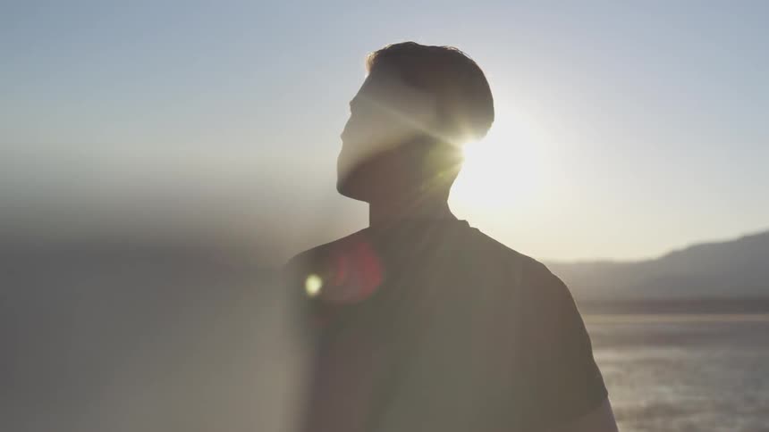 Man standing on a dry desert with bright sun shining down