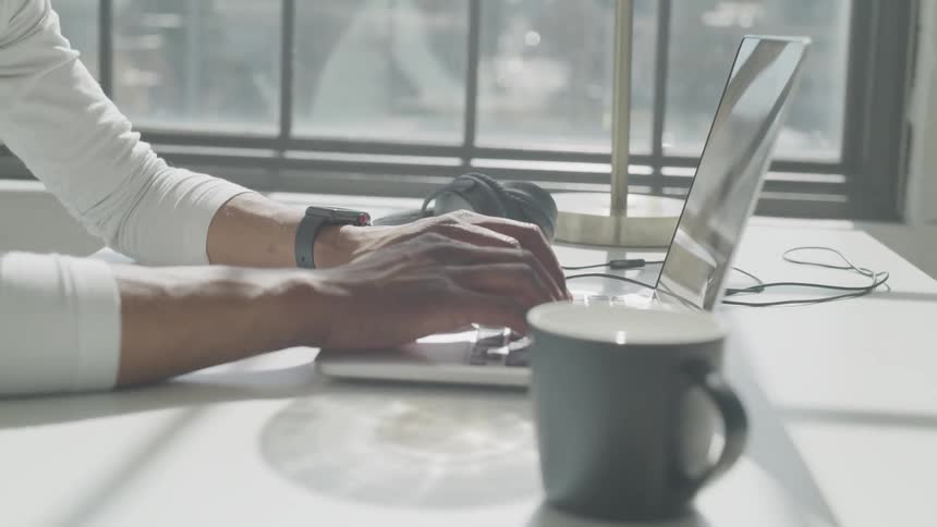 A man sitting at a desk typing on a laptop