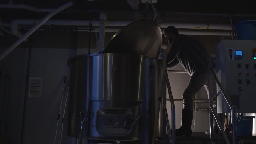 A man works on a vat in a brewery