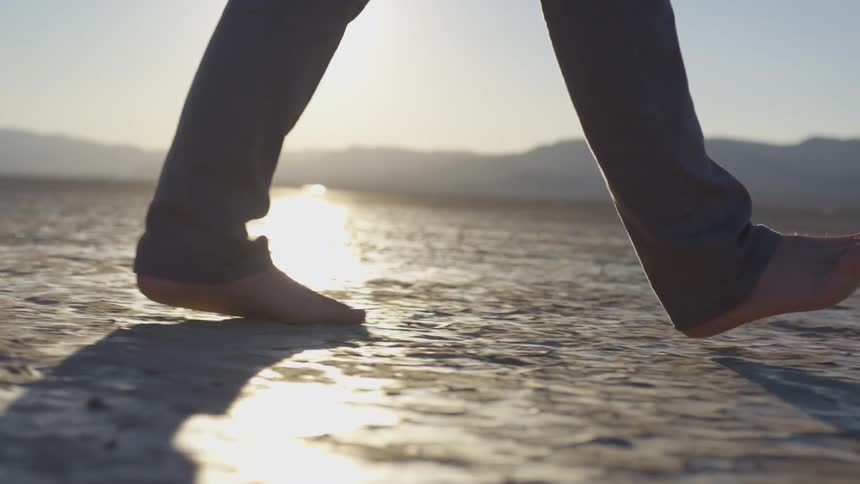 A person is walking barefoot in the desert