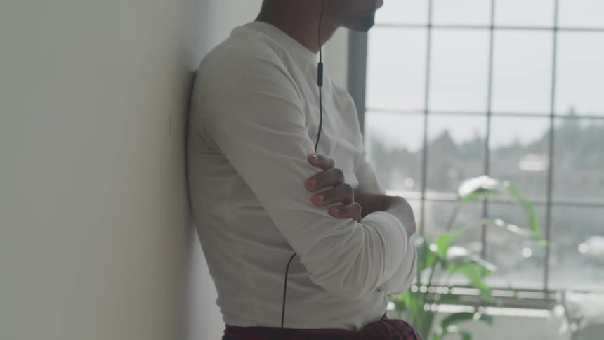 A man leans against the wall with his arms crossed