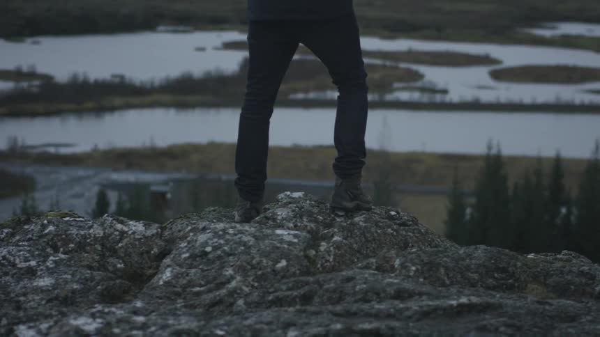 A person wearing hiking boots standing on a rocky ledge