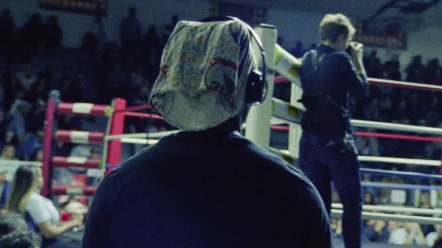 Man watches two people boxing in a gymnasium