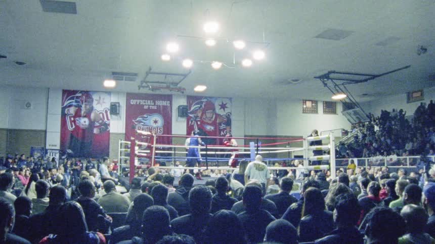Boxers fight in the ring in front of a crowd