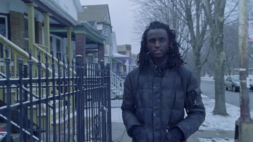 A man on a jacket walking down a street in a snowy day