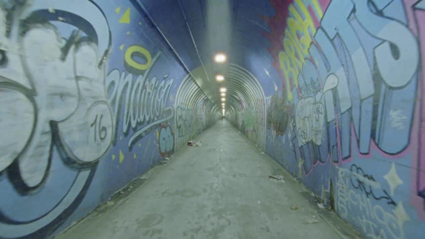 Graffiti covers the walls of a long tunnel