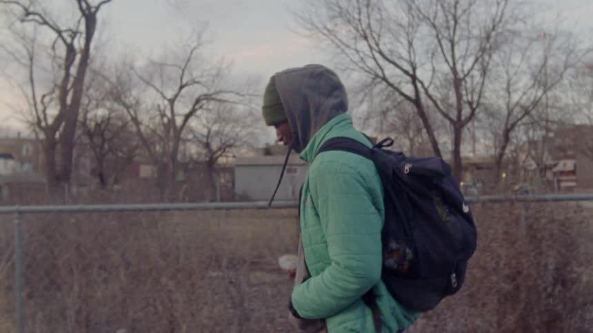 A young man wearing a backpack walks with a companion
