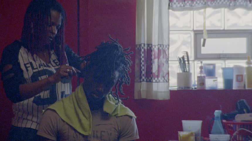 A woman cutting a man's hair while they talk