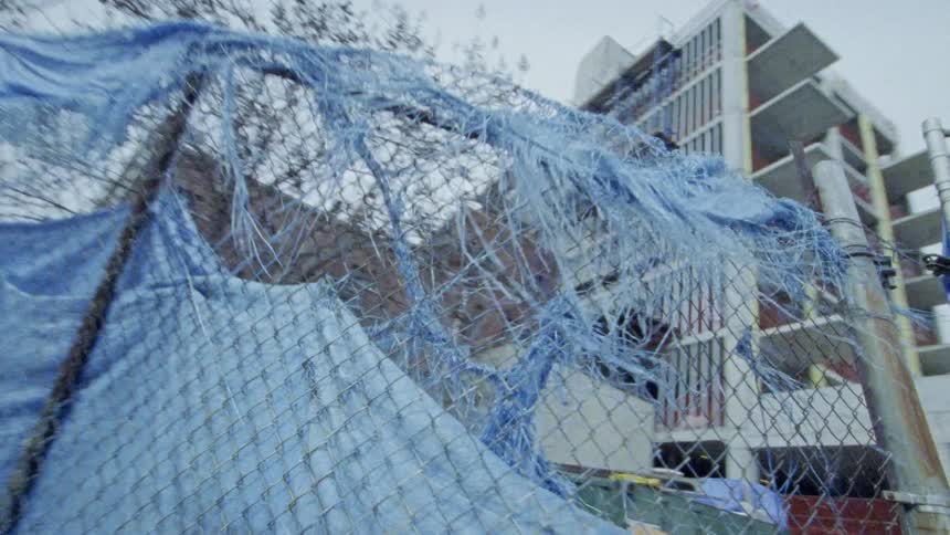 A fence separates the camera from a tall building