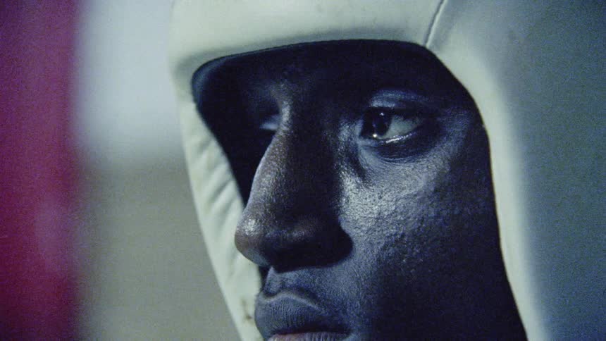 A boxer wearing a sparring helmet looks around