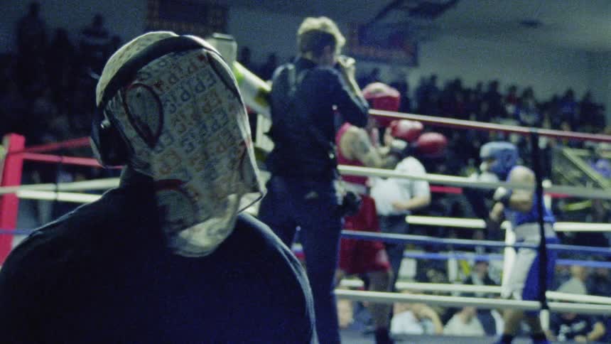 A boxing match is in the background of a person wearing headphones