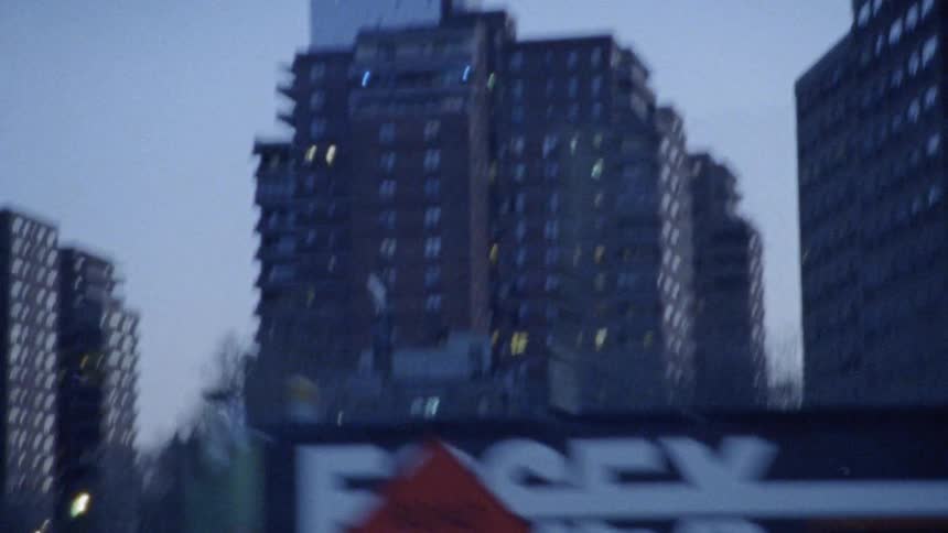 A car travels in a city at dusk