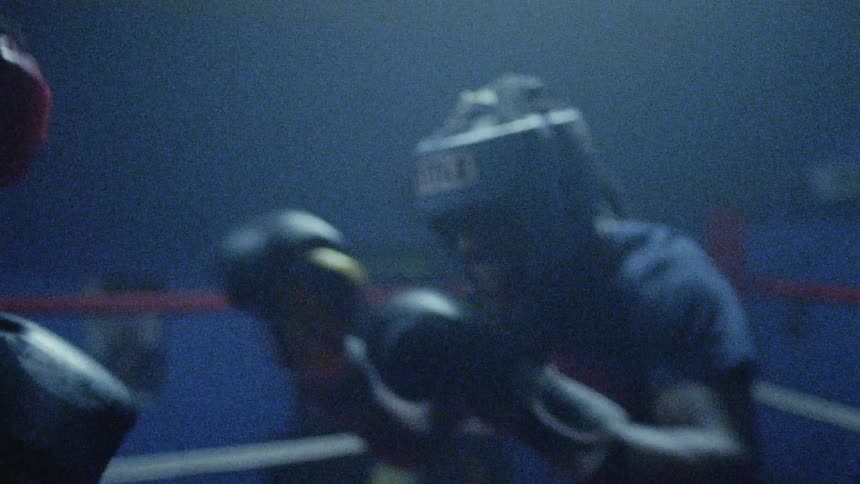 Lights flash while two boxers fight in a boxing ring