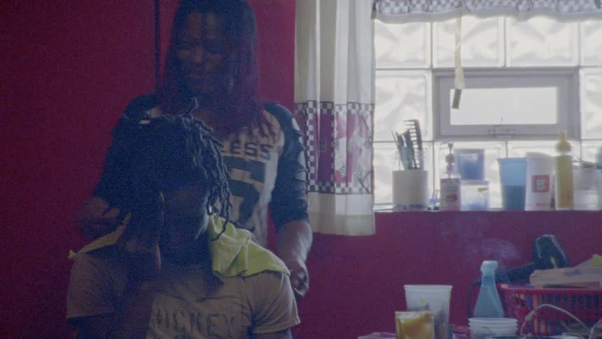 A woman is braiding a man's hair