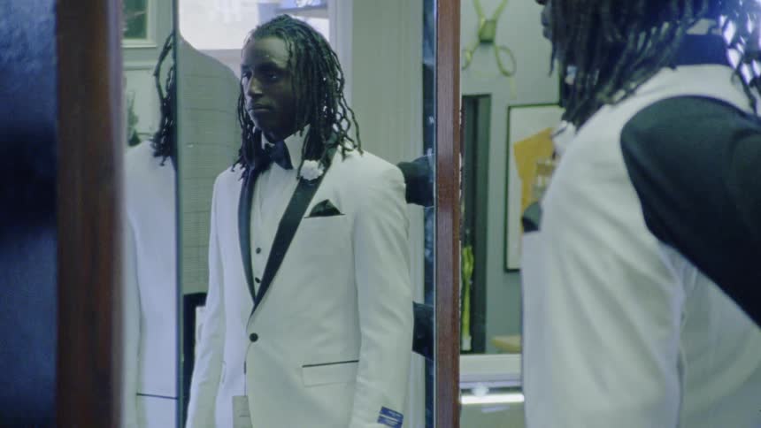 A man is posing in front of a mirror wearing a tux