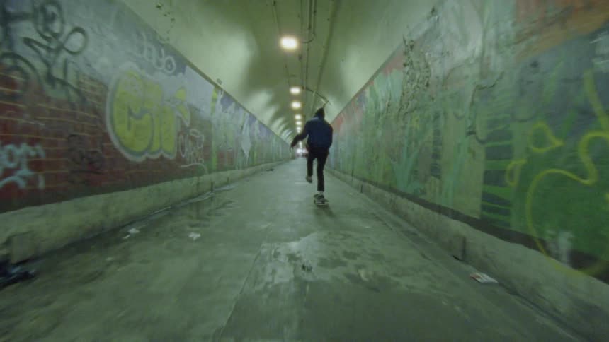A person is skateboarding through a tunnel