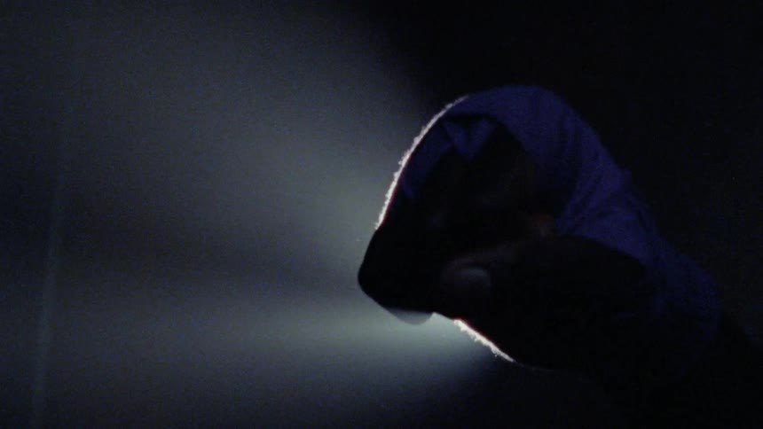 A man closes his cloth wrapped fist in front of a spotlight