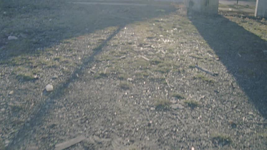Rock and weed covered ground in front of houses