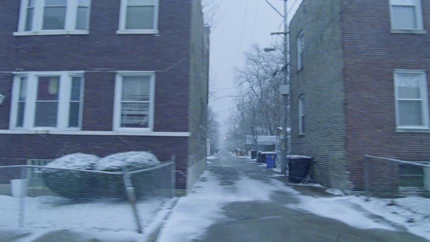 A car driving along a neighborhood while snow falls