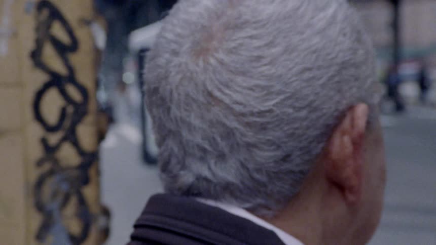 The back of a man's head waiting on the corner of the street