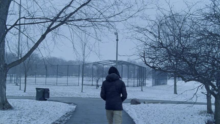 Man walks down sidewalk with snow on the ground