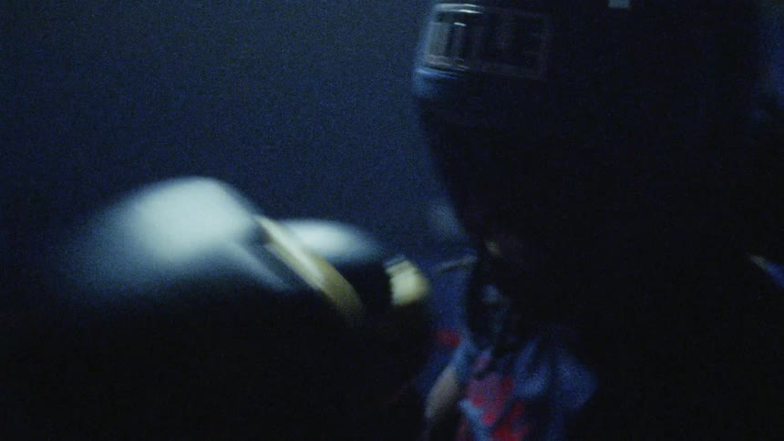 A man fighting a boxing match under strobing lights