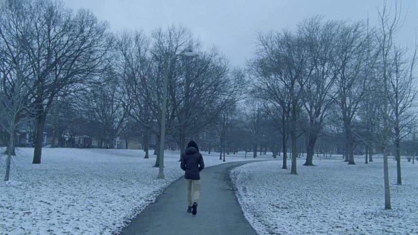 A person walking a pathway by snow covered grass