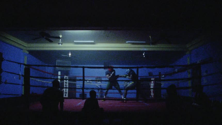 Two boxers fight it out in front of people under flashing lights