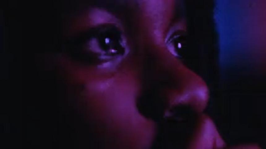 A woman watching a screen on a dark room