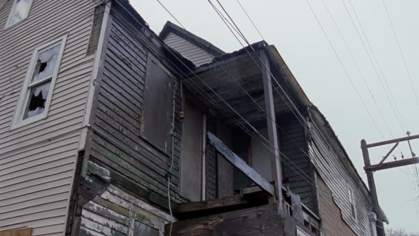 The house is in shambles with broken windows and porch