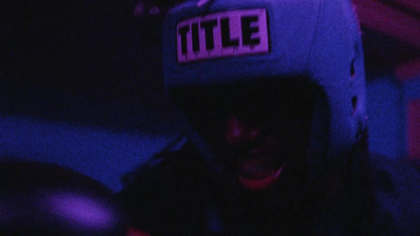 A man is boxing in the dark and lights are flashing