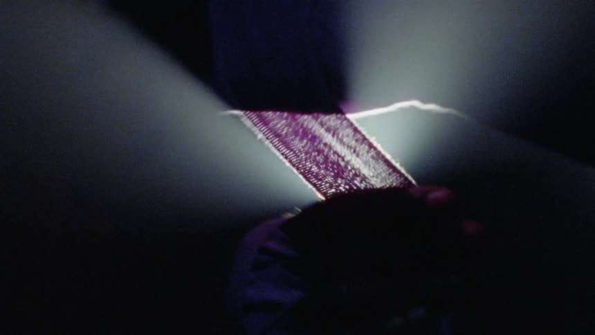 A man wraps his fist with cloth in front of a spotlight