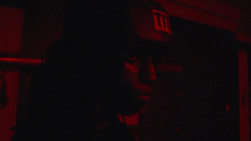 Boxer wearing head gear stands in deep thoughts in dark room