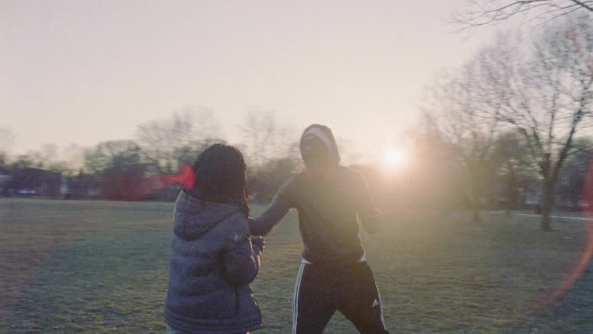 Two people are practicing fighting moves in a park area