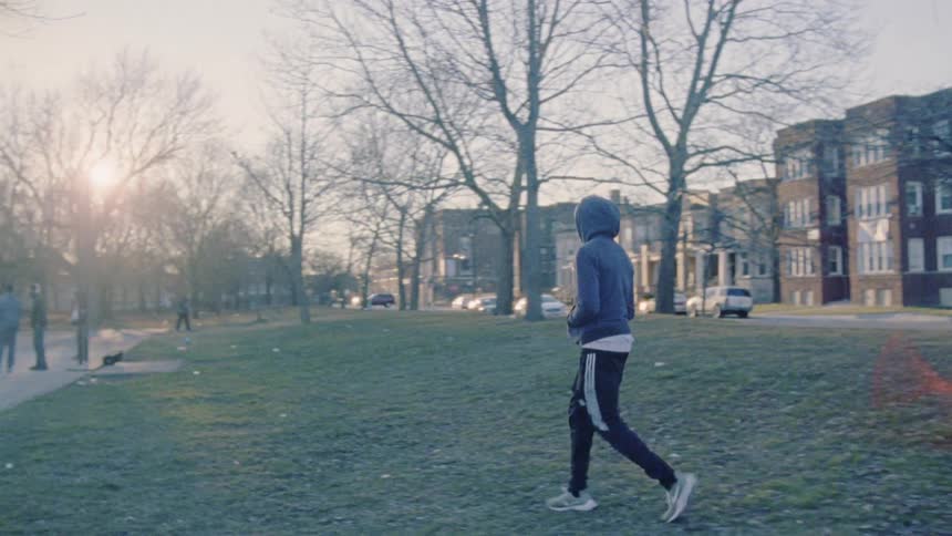A man walks through a park to a basketball court