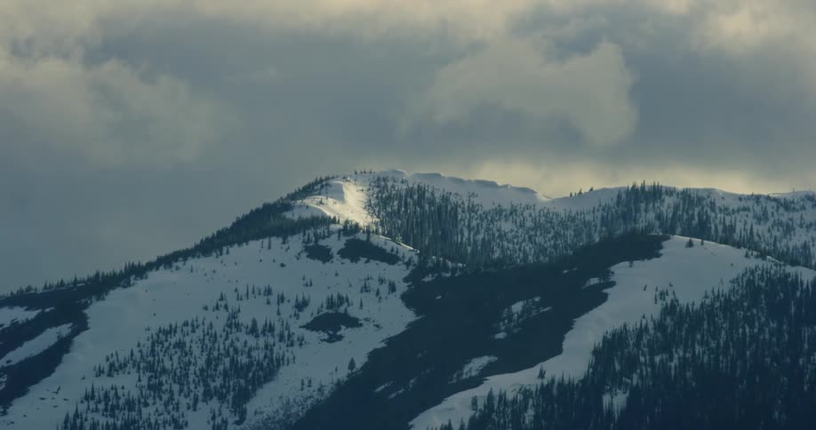 Dark clouds are blown past the mountaintop