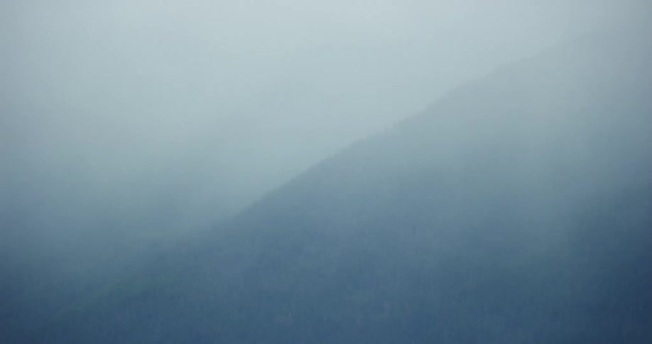A misty fog surrounds and engulfs the entire mountain  top