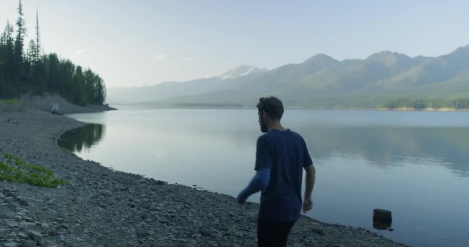 Man walks along a rocky shore bank