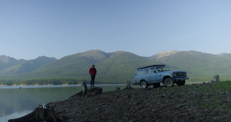 A man stands on a rock next to a lake