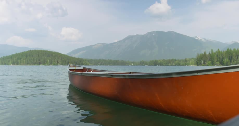 Orange canoe floating in the water in front of a mountain