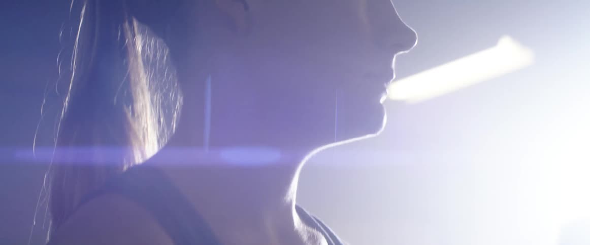 A bright light shines on a young woman standing in a room