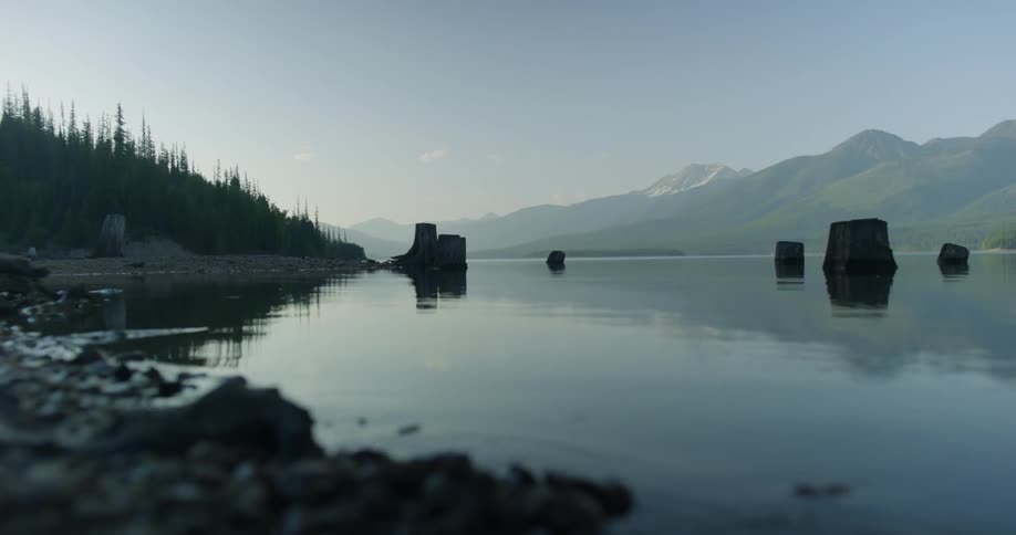 Water ripples next to a forest with mountains in the distance