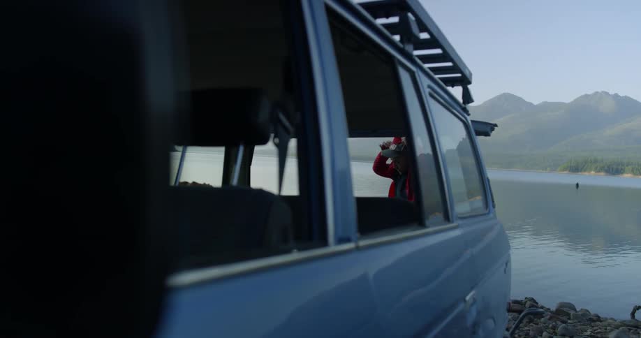 A man closes his car door by the side of the lake