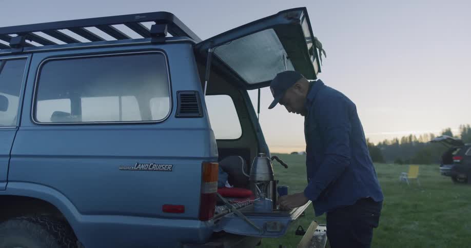 Man walks to the back of his vehicle and examines the items inside