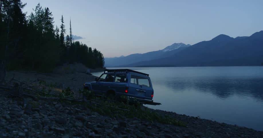 The truck drives over the rocks by the lake
